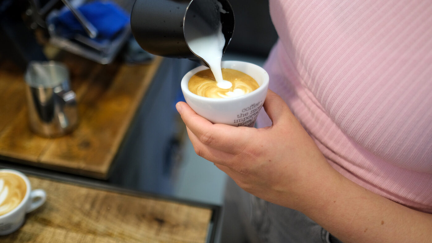 Latte Art wird eingegossen: seidiger Milchschaum trifft Espresso